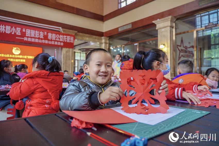 孩子高兴的展示自己的剪纸作品。翁光建摄